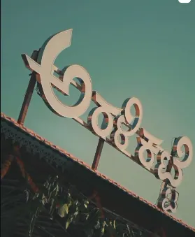 Aralikatte signboard in Kannada lettering against the sky