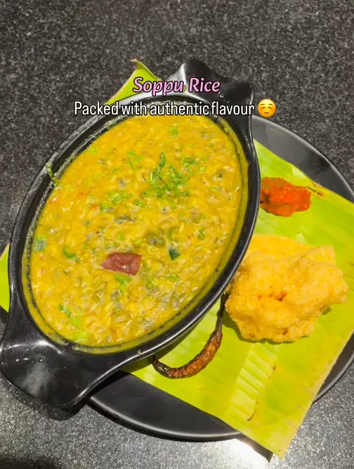 Soppu rice served in a steel dish beside a sweet on a banana leaf
