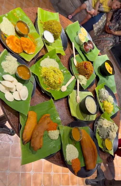 Overhead view of banana-leaf plates of South Indian dishes laid out on a table